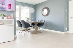 A dining area with a table and chairs, a pendant light, and a mirror on the wall. - Holiday apartment with 2 bedrooms (Timmendorfer Strand)