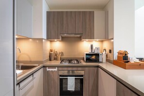 Eine moderne Küche mit Gaskochfeld, Backofen und Kaffeemaschine.