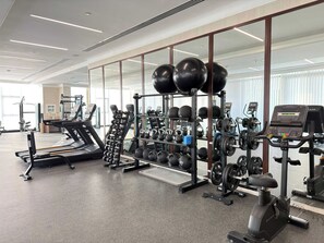 A gym with treadmills, weight machines, and free weights. - Rentico | Skyhills Studio | Pool, Sauna, Gym, BBQ (Dubai)