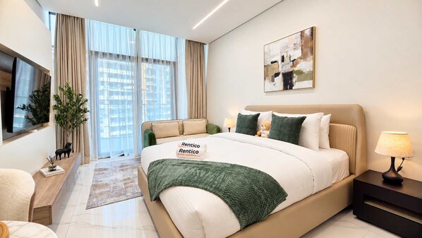 Ein modernes Hotelzimmer mit einem großen Bett, einem Flachbildfernseher, einem Schreibtisch und einem Fenster mit Vorhängen.