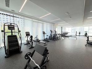 A gym with various exercise equipment, including treadmills, stationary bikes, and weight machines. - Rentico | Skyhills Studio | Pool, Sauna, Gym, BBQ (Dubai)