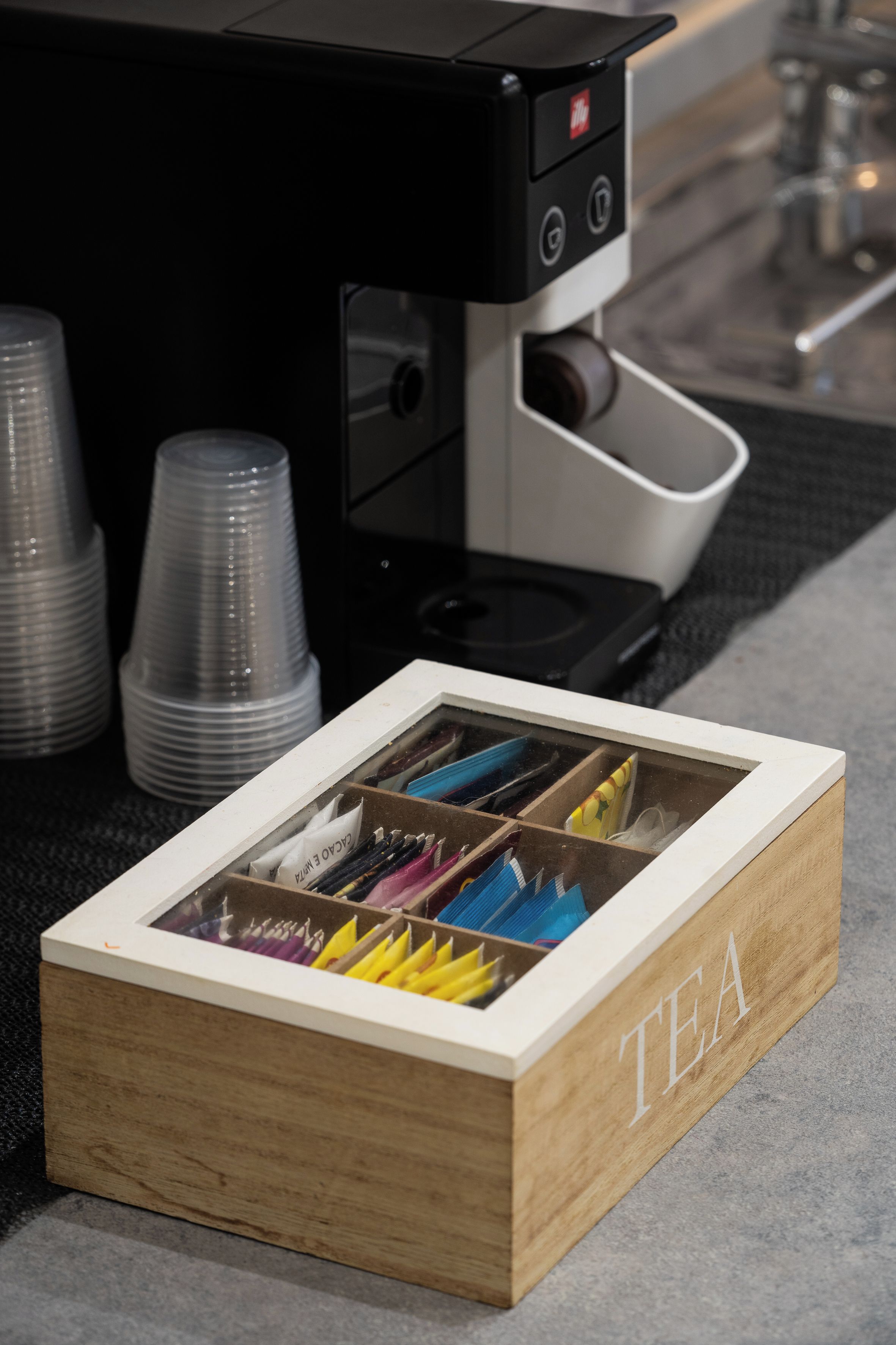 Une boîte en bois étiquetée « THÉ », comportant des compartiments contenant divers crayons de couleur.