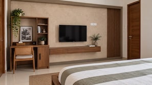 A bedroom with a bed, a desk with a chair, a television, and a wardrobe. - Awi House (Jimbaran)