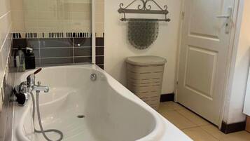 A bathroom with a freestanding bathtub, a window, a towel rack, and a door.