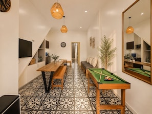 A room with a billiards table, a television mounted on the wall, and a dining area with a bench and table. - Quarter Balcony Apt 3Brs . Free Laundry . Sleeps 8 by Anamoi (Hà Nội)