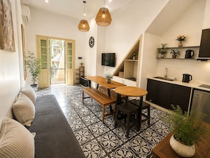 A modern kitchen with a dining area, a TV mounted on the wall, and a staircase leading to an upper level. - Quarter Balcony Apt 3Brs . Free Laundry . Sleeps 8 by Anamoi (Hà Nội)
