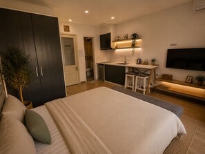 A modern bedroom with a large bed, a small kitchenette, and a TV mounted on the wall. - Quarter Balcony Apt 3Brs . Free Laundry . Sleeps 8 by Anamoi (Hà Nội)