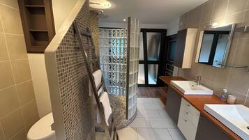 Een moderne badkamer met een douche, toilet en wastafel.