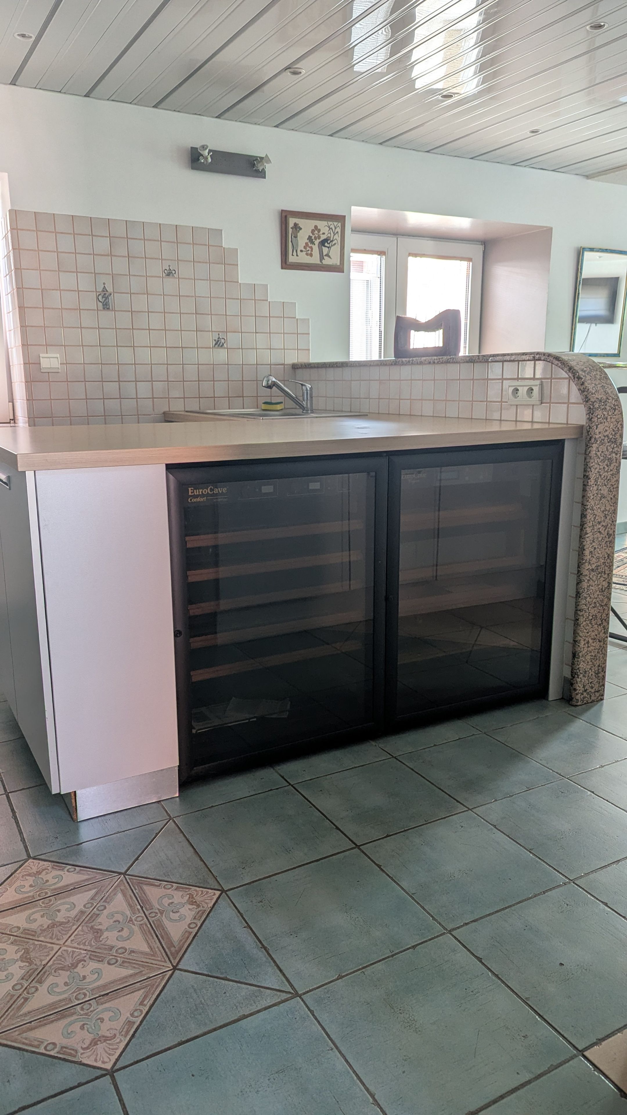 Una cocina con lavavajillas integrado, salpicadero de azulejos y ventana que proporciona luz natural.