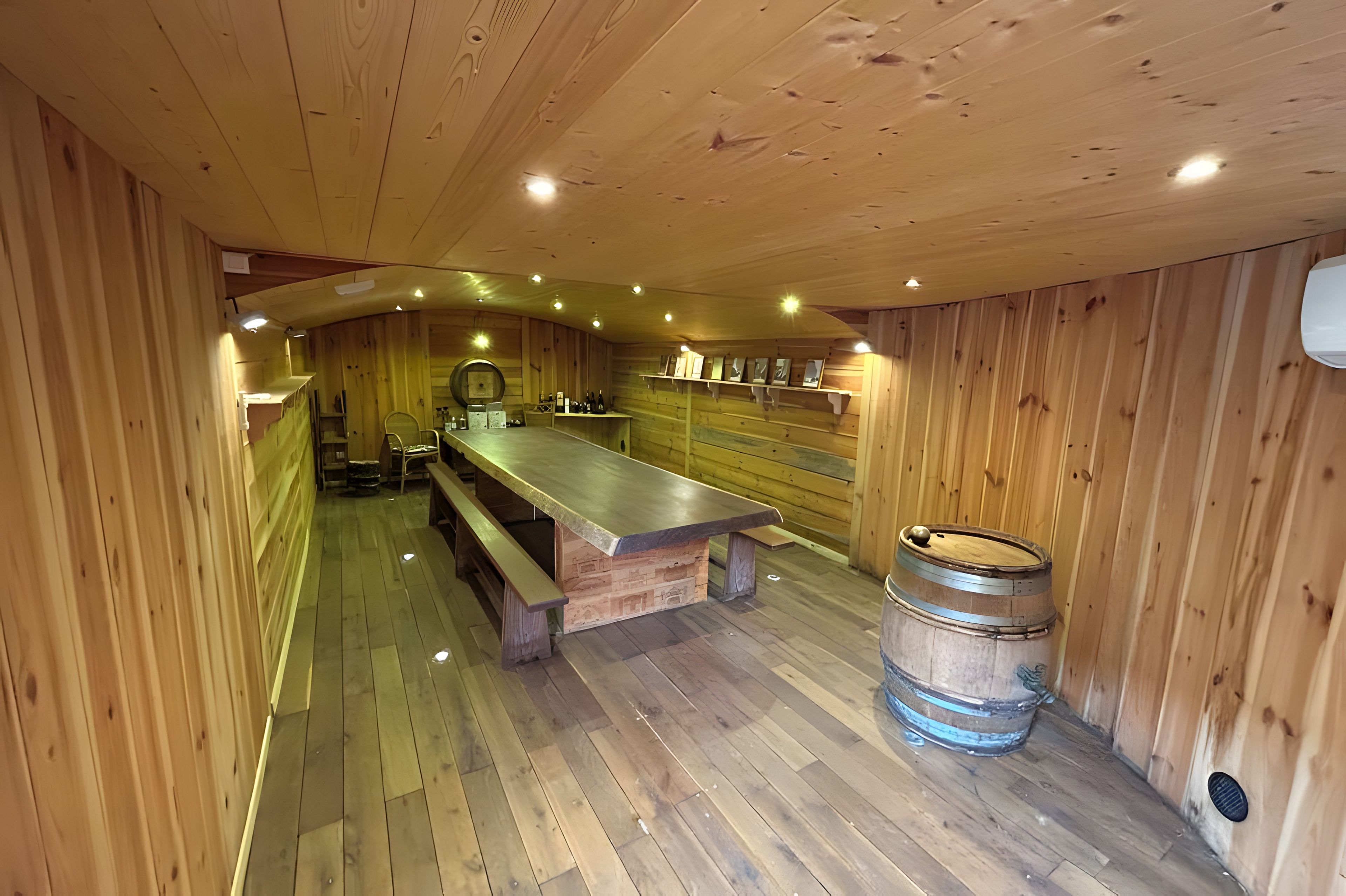 Een houten interieur met een lange bank, een tafel en een vat.