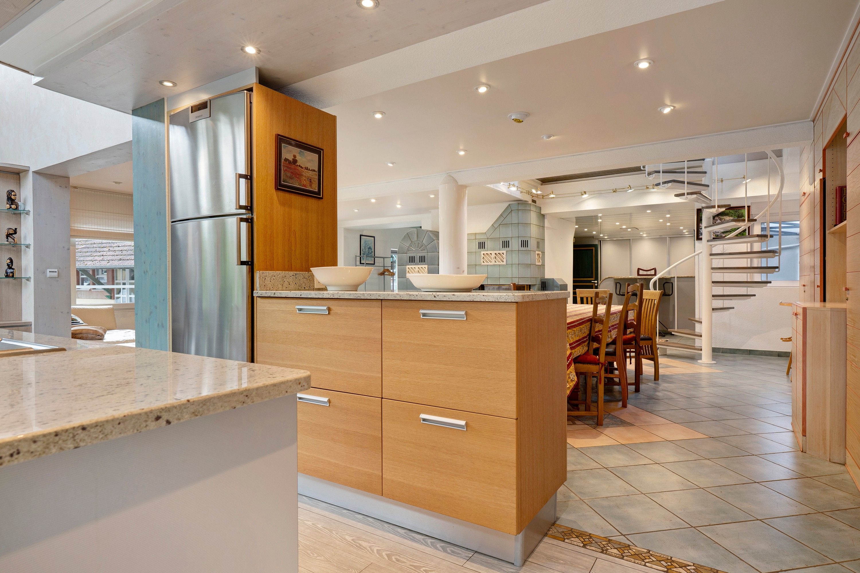 Een moderne keuken met een centraal eiland, houten kastjes en een roestvrijstalen koelkast.