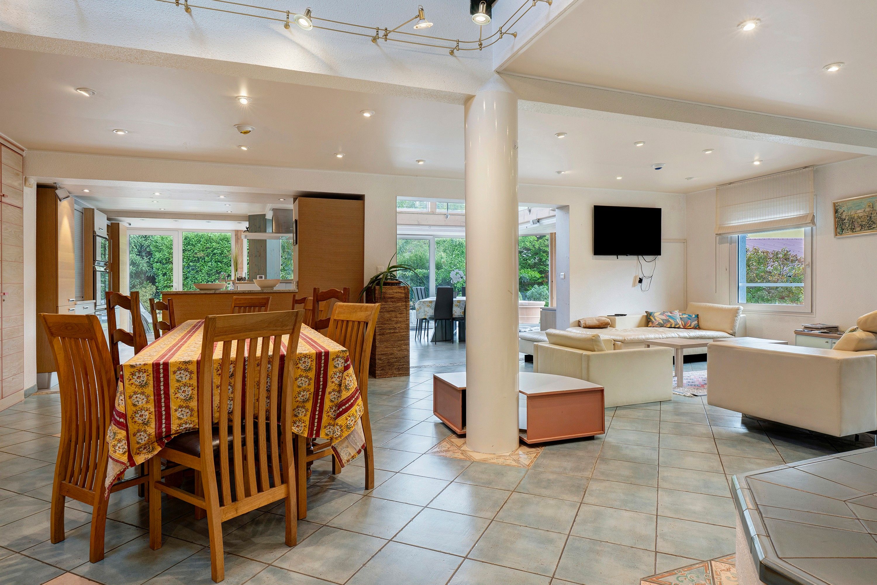 Un grand espace de vie comprenant une table à manger, des chaises, un canapé et un téléviseur.