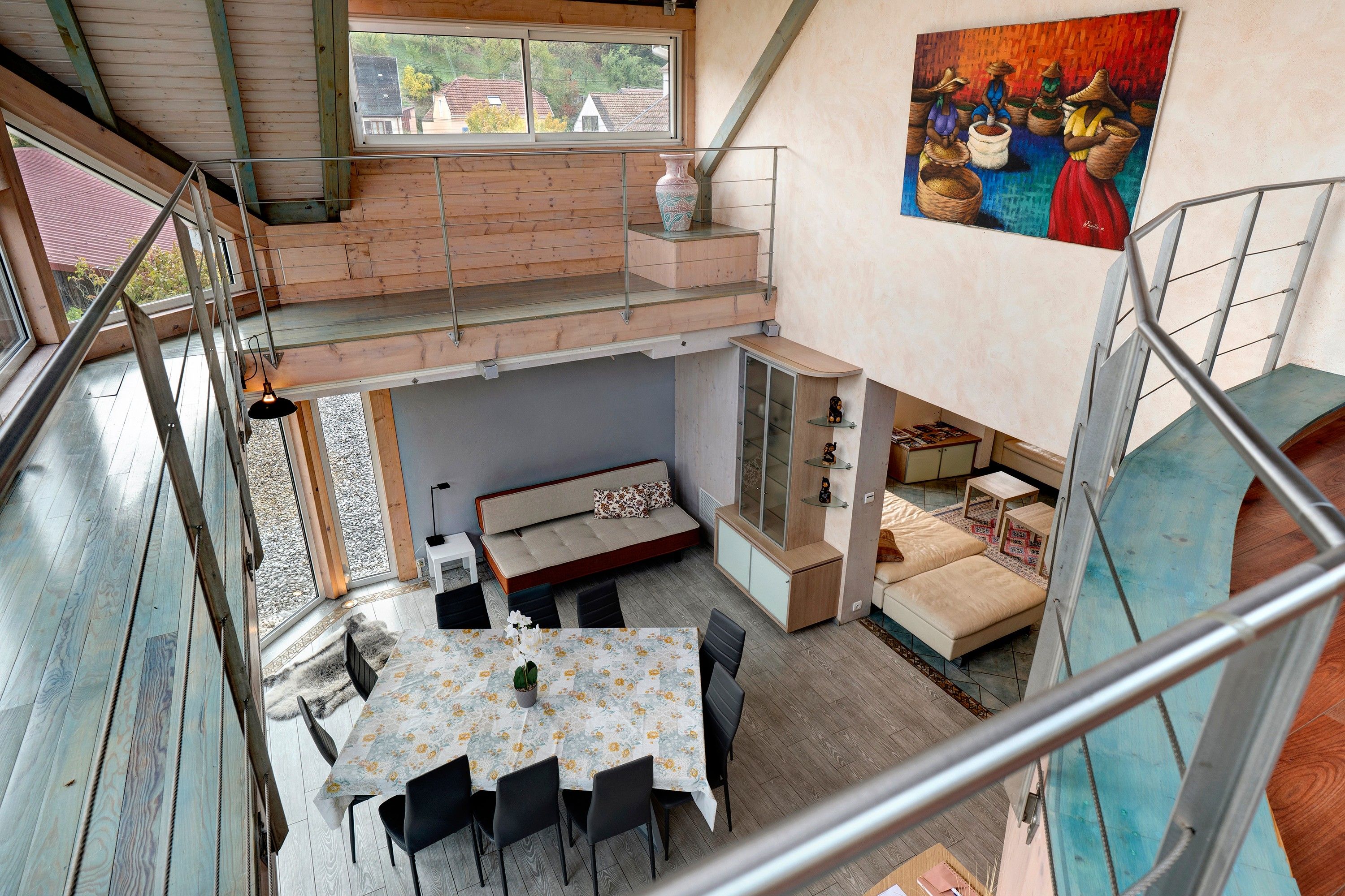 Ein mehrgeschossiges Interieur mit Essbereich, Sofa und Kunstwerken.