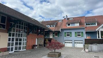 Ein Innenhof mit einem Baum mit roten Blättern, einer Steinsitzbank und einem Gebäude mit einer Garagentür.