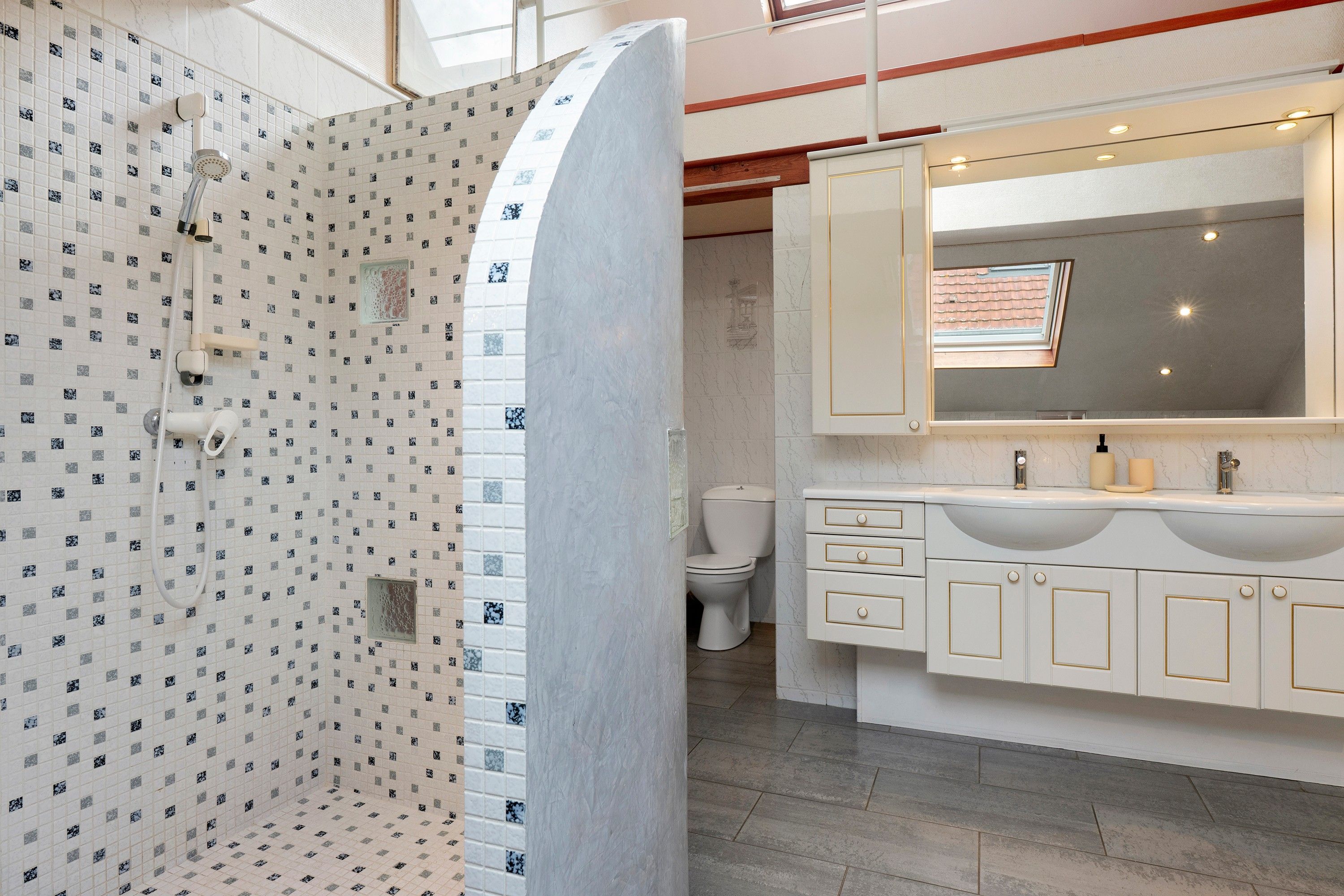 Une salle de bain équipée d’une douche, de toilettes et d’un meuble-lavabo avec un miroir et un évier.