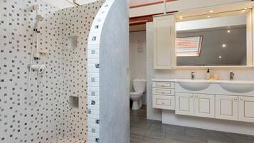 Een badkamer met douche, toilet en wastafelmeubel met spiegel en wastafel.