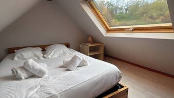 Un dormitorio con cama, mesita de noche, ventana y vistas al exterior.