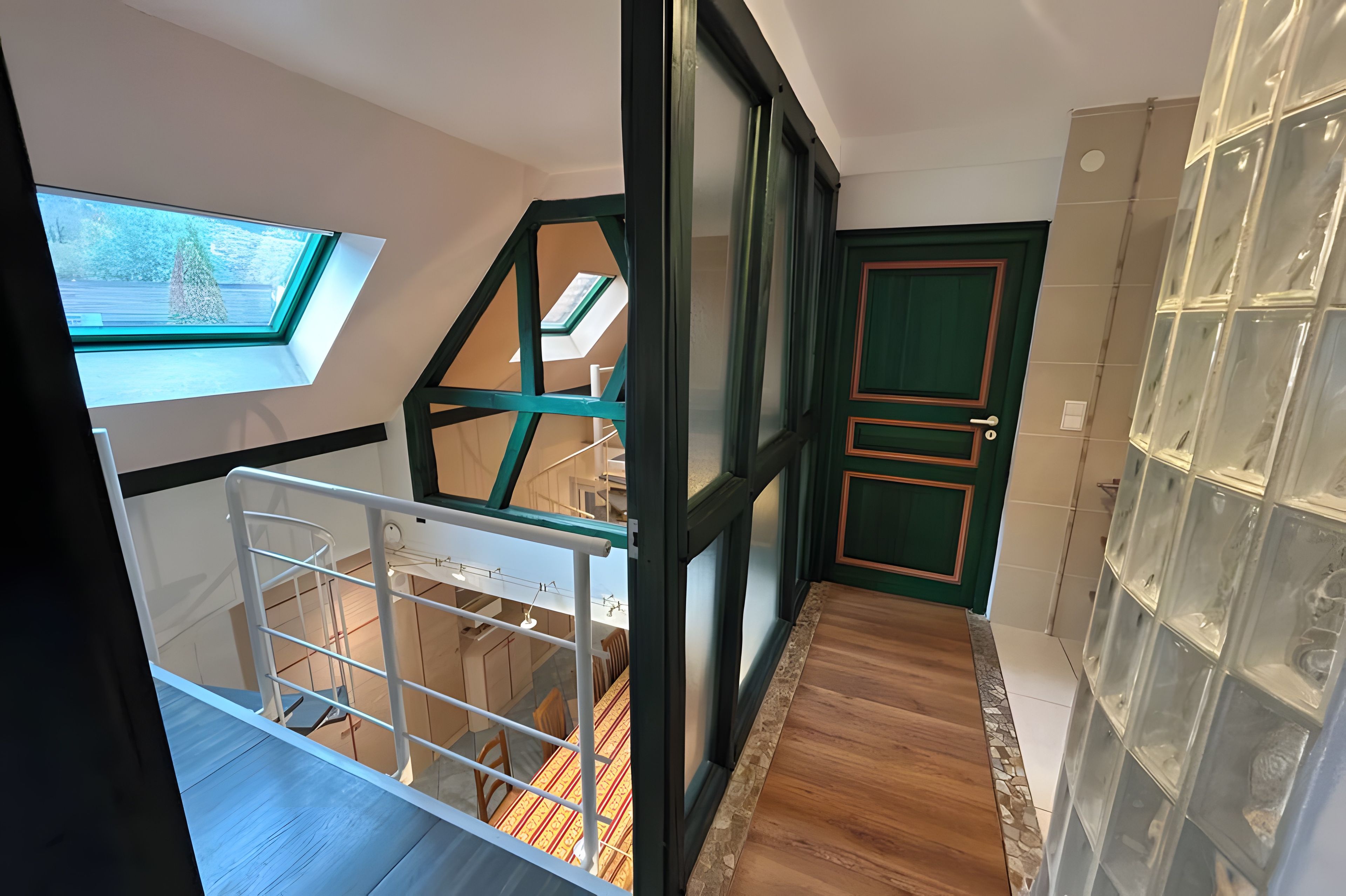 Un intérieur moderne agrémenté d’une verrière, d’un escalier et d’une porte dotée d’un cadre vert.