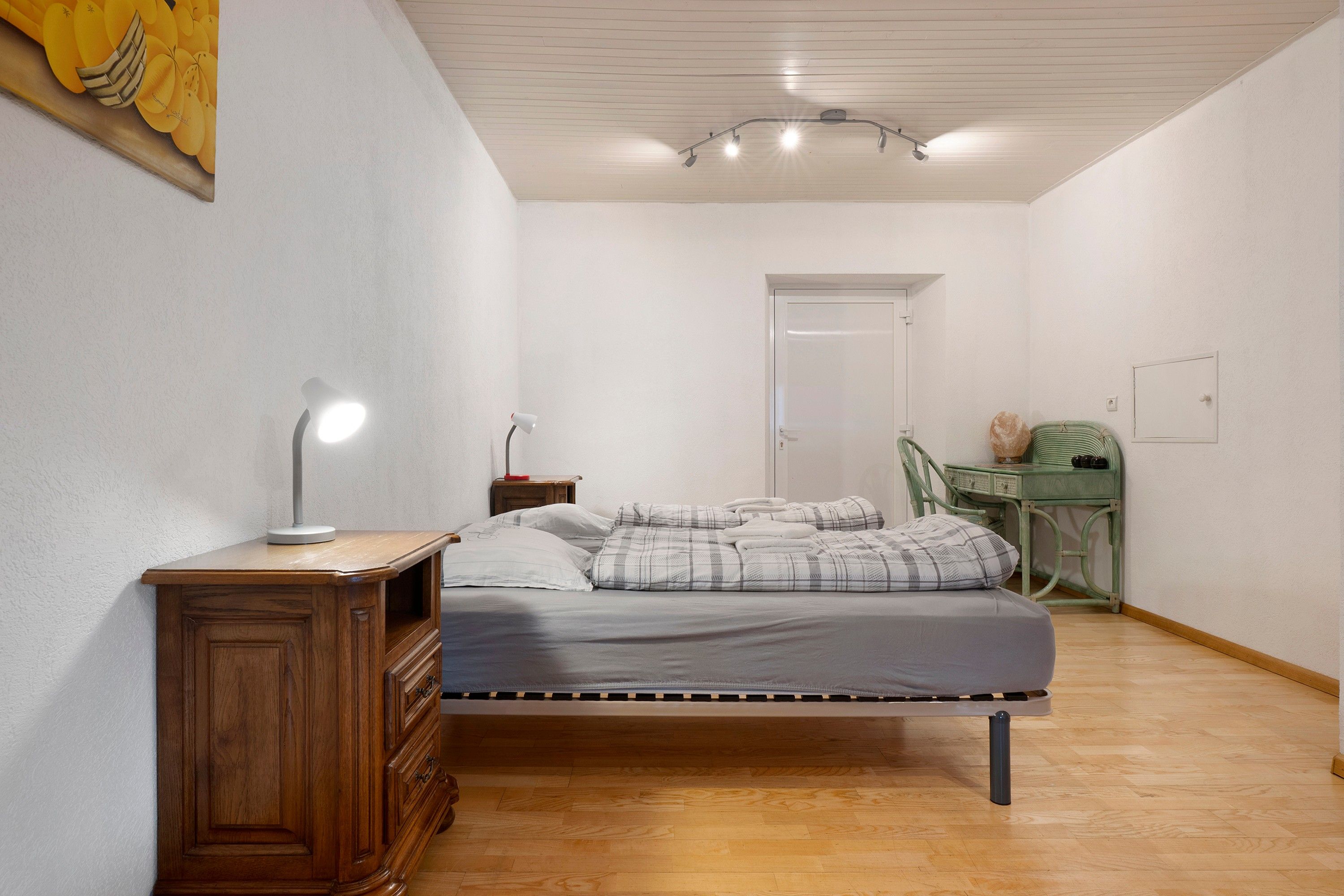 Une chambre à coucher comprenant un lit, une table de chevet, une lampe et un bureau avec une chaise.