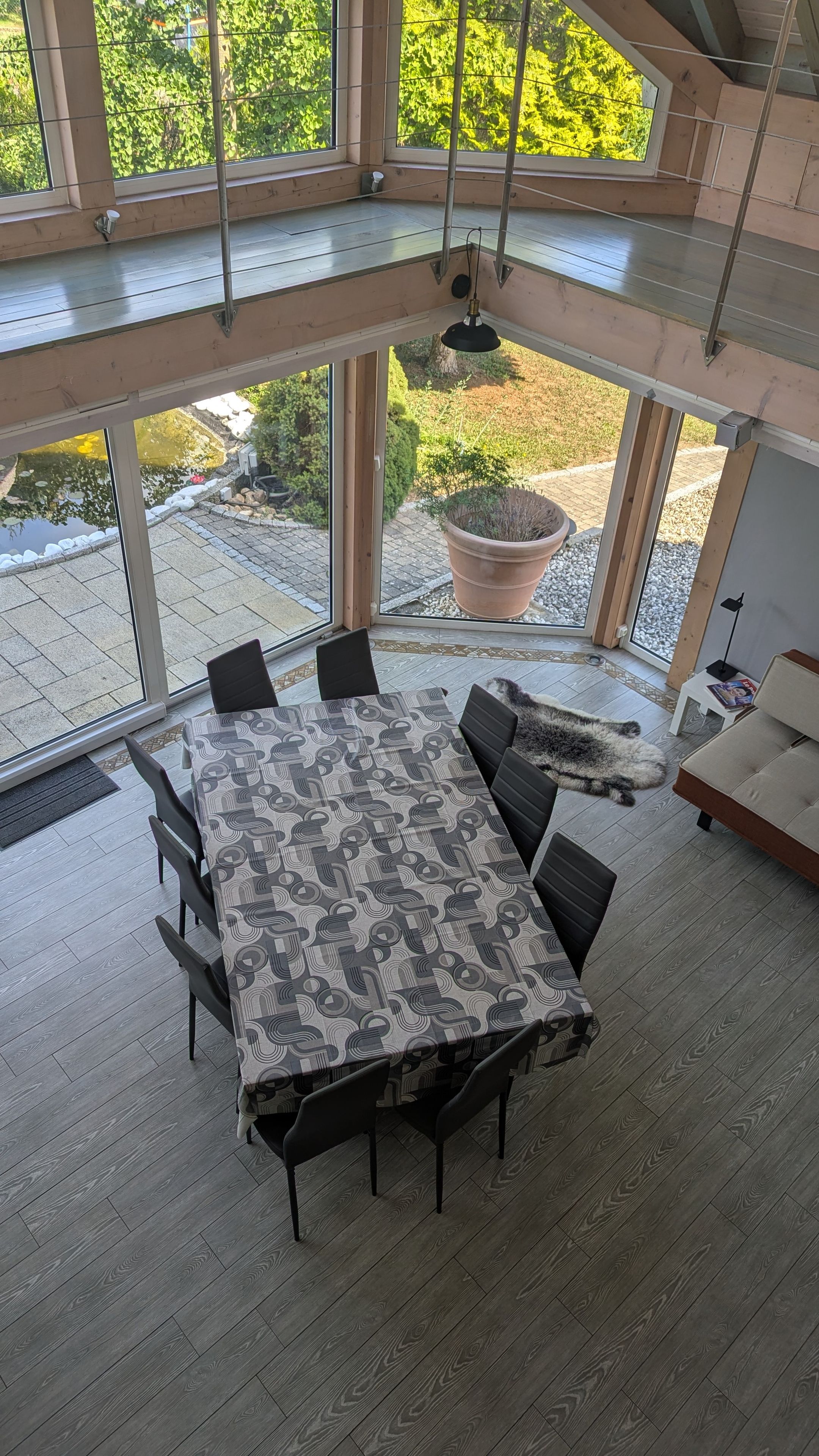 Ein Essbereich mit Tisch und Stühlen, großen Fenstern und Blick auf einen Garten.