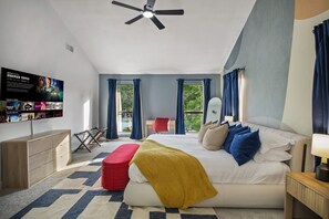 Ein modernes Schlafzimmer mit einem Bett, einem Fernseher, einem Deckenventilator und Blick ins Freie.