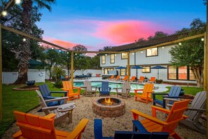 Ein Außenbereich mit Terrasse, Feuerstelle, Liegestühlen und Pool.