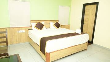 A neatly made bed with a wooden frame and white bedding, a wooden chair, and a small table with a glass top.