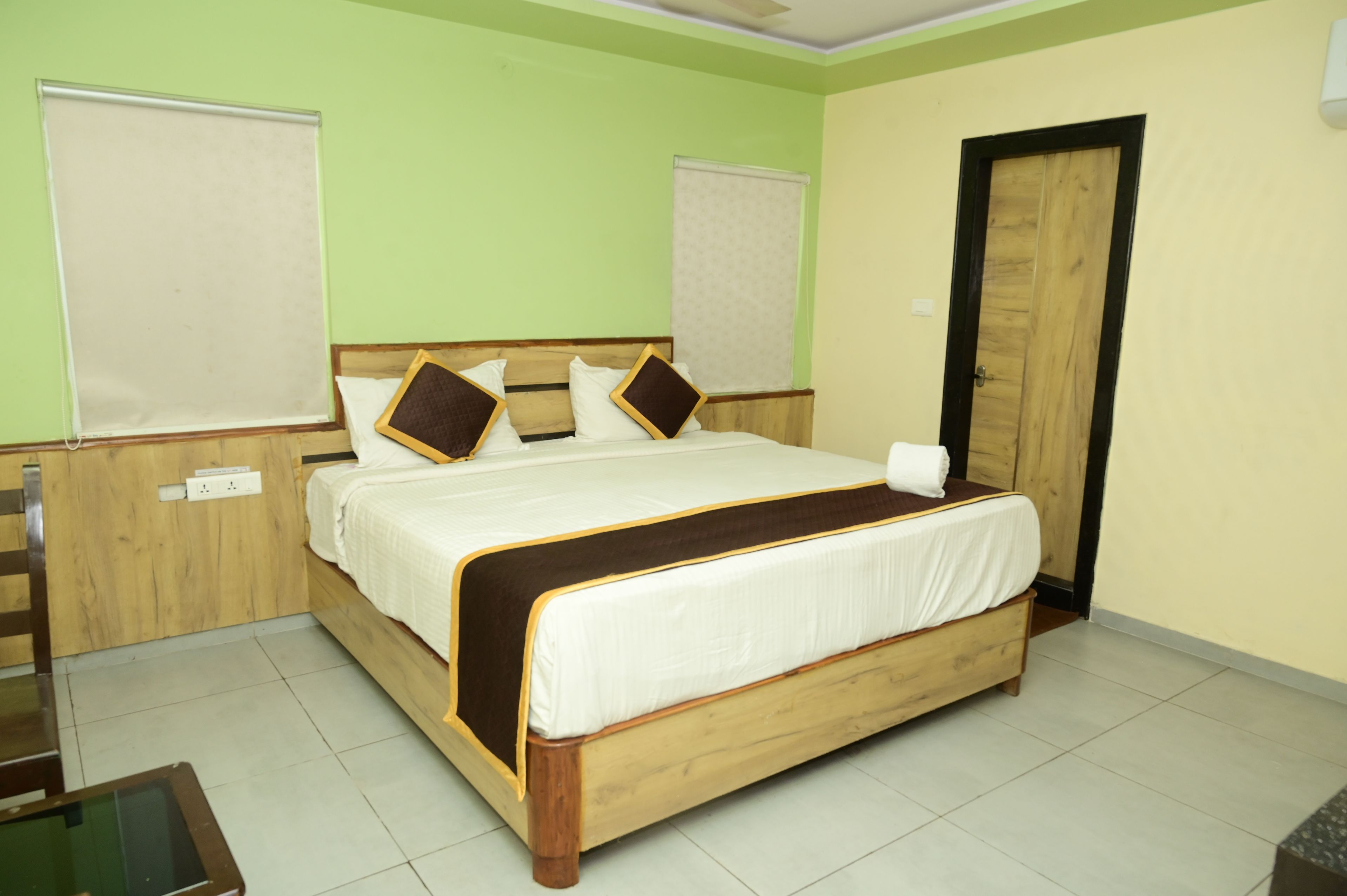 A bedroom with a wooden bed, green walls, and a door.