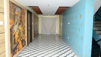 A hallway with patterned flooring, a mural on the left wall, and a blue patterned wall on the right.