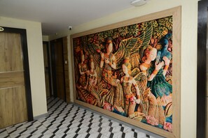 Un corridoio con un grande murale, pavimento piastrellato e una porta in legno.