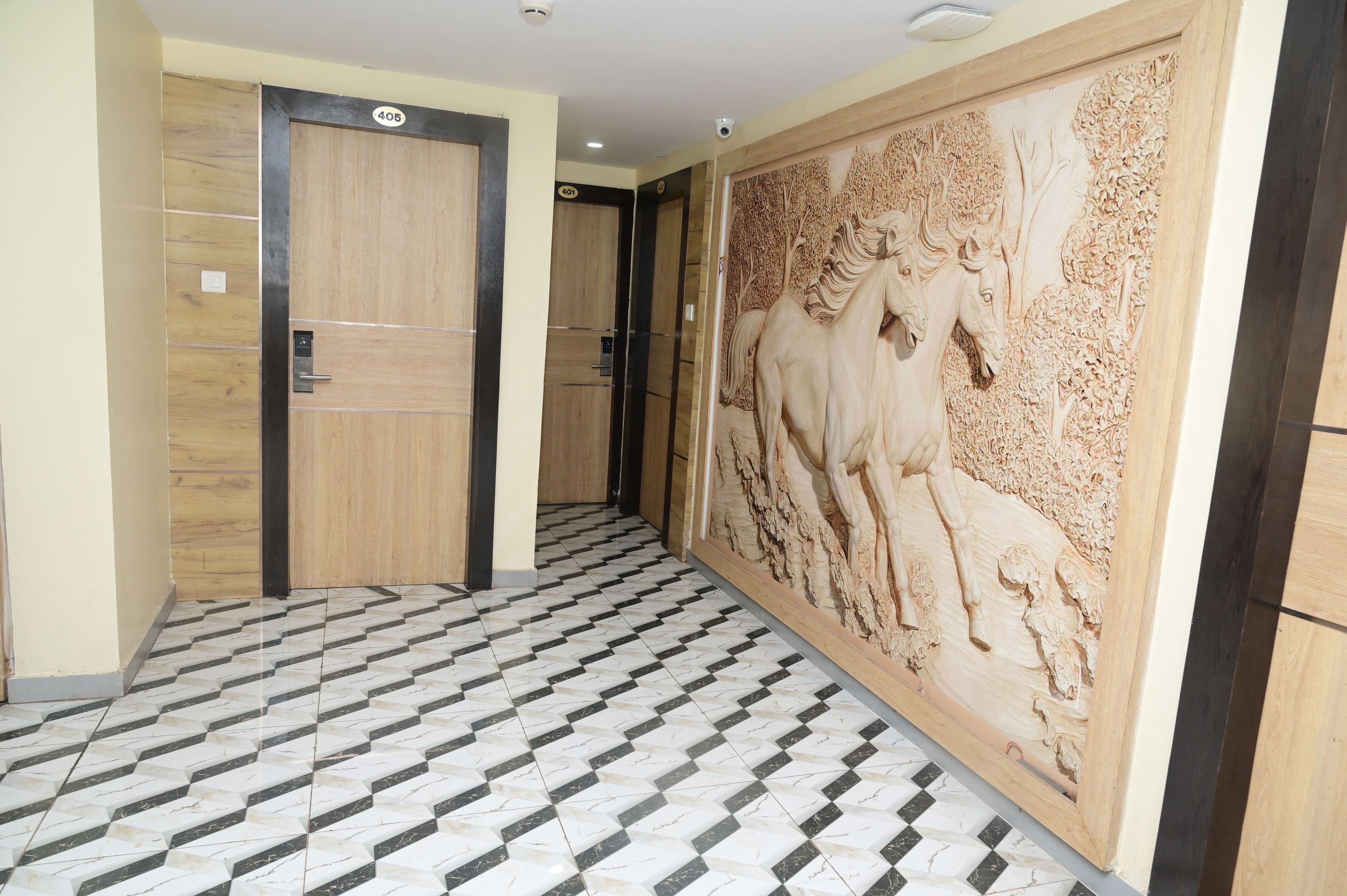 Un pasillo con piso estampado, puertas de madera con números y un detallado relieve en la pared.