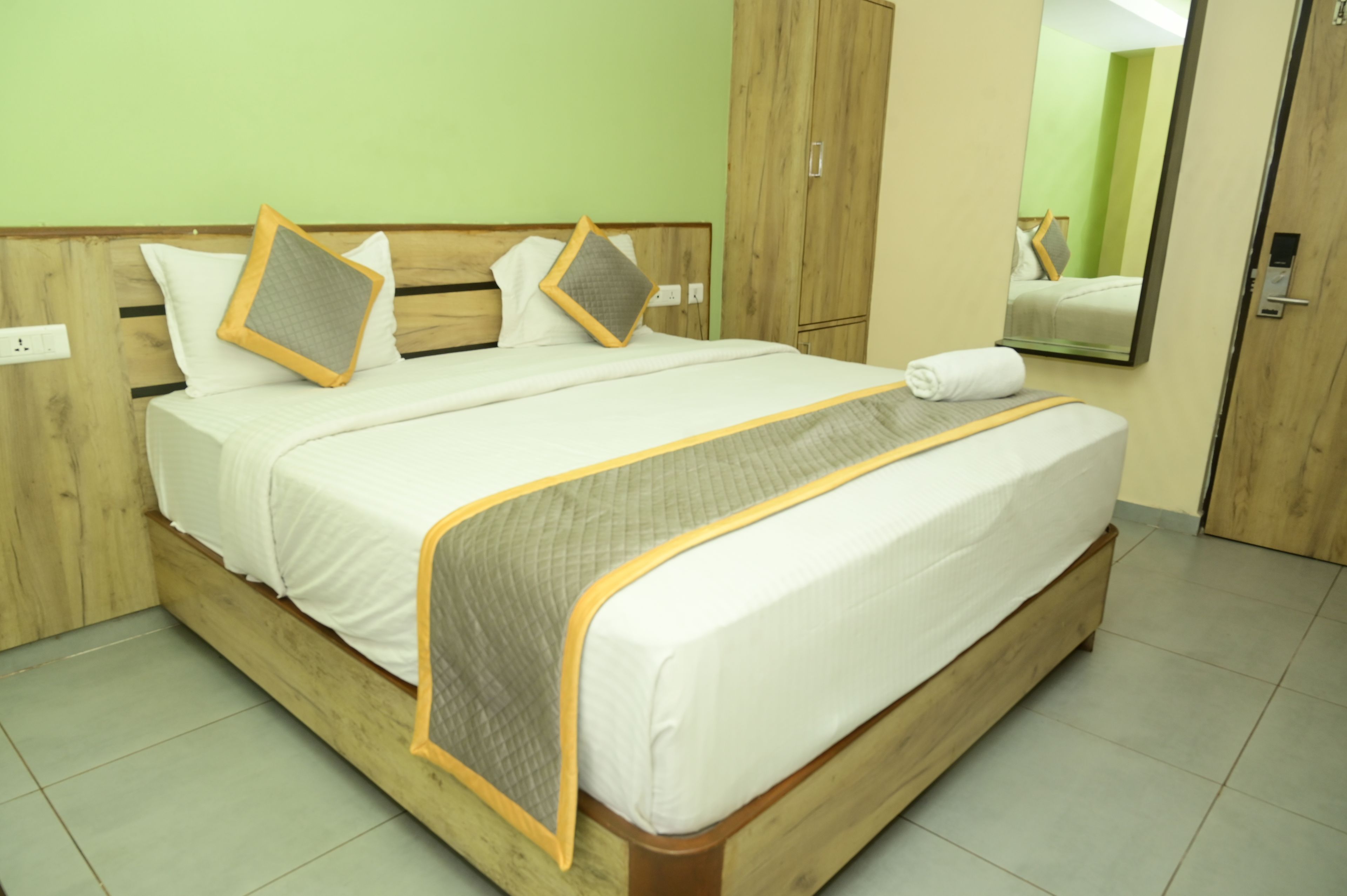 Una habitación de hotel con un cabecero de madera, ropa de cama blanca y un espejo en la pared.
