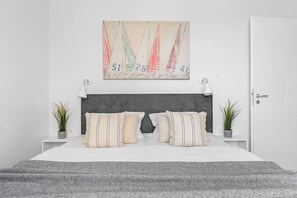 Ein modernes Schlafzimmer mit einem großen Bett, zwei Nachttischen, einer Kopfteil und einem an der Wand hängenden Gemälde.
