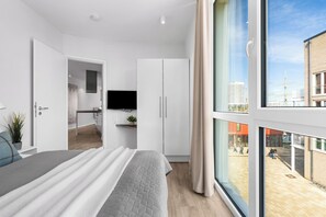 Una camera da letto moderna con una grande finestra, un letto, un armadio e un angolo cottura.