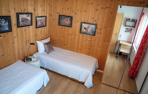 A room with two single beds, wooden walls, and framed pictures on the wall. - Cozy vacation rental for families with mountain views, midday sun, a pool, and a sauna (Davos)