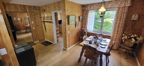 Interior de madeira com área de refeições, cozinha e um espelho refletindo o ambiente.
