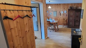 A wooden interior with a dining area, a kitchen, and a hallway with a coat rack. - Cozy vacation rental for families with mountain views, midday sun, a pool, and a sauna (Davos)