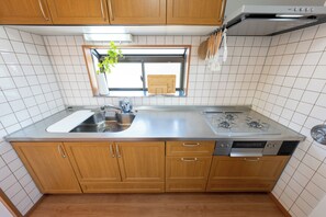 A kitchen with wooden cabinets, a stainless steel sink, a window with a view, and a gas stove. - Opening Sale | Private Rental | 3 min from the beach, 5 min from the train station | Perfect for visiting Enoshima and Kamakura (藤沢市)