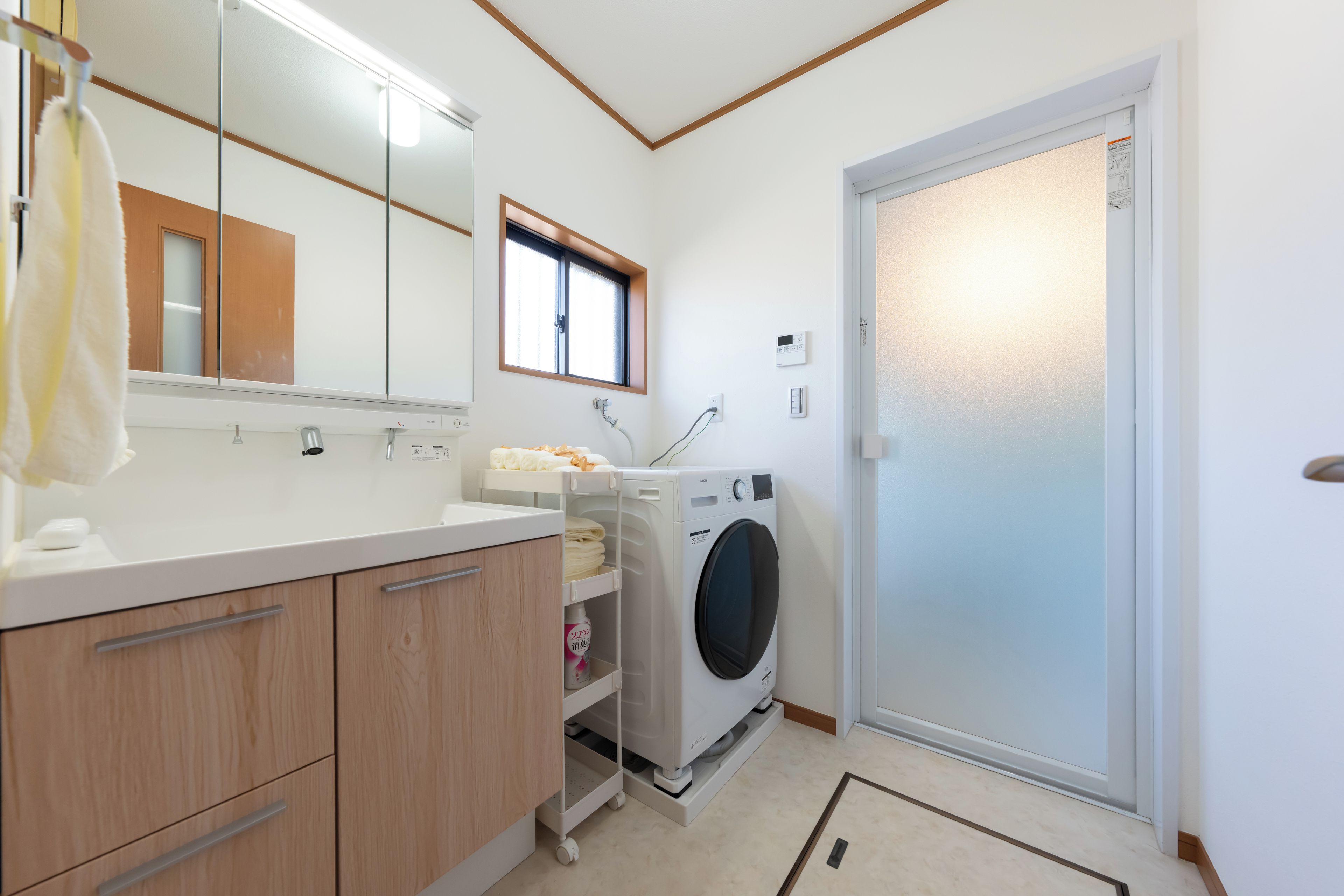 A modern bathroom with a built-in washing machine, a mirror, and a towel rack.