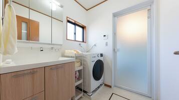 A modern bathroom with a built-in washing machine, a mirror, and a towel rack.