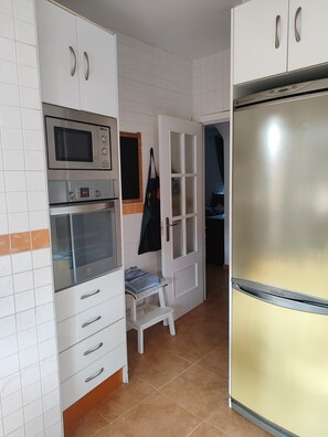 A kitchen with white cabinets, a microwave, an oven, a refrigerator, and a small step stool. - 3-bedroom townhouse with a pool and a paddle tennis court (lepe)