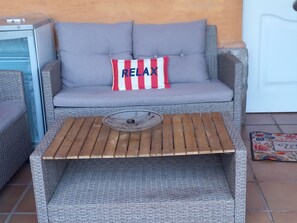 A wicker sofa with a cushion labeled 'RELAX' and a wooden coffee table with a metal plate. - 3-bedroom townhouse with a pool and a paddle tennis court (lepe)