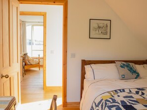 A bedroom with a bed, a wooden door, a framed picture on the wall, and a view of another room through an open door. - Beautiful private villa for 6 people with WIFI and patio (Isle Of Skye)