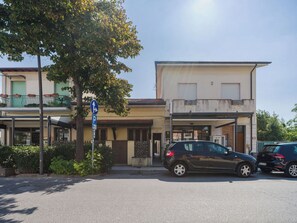 Straßenszene mit parkenden Autos, einem Gebäude mit einer Garageneinfahrt und einem blauen Parkschild.