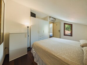 Ein Schlafzimmer mit Bett, Kleiderschrank, Nachttischlampe und Fenster.