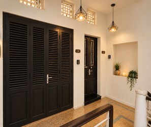 A hallway with a black door, a number plate, a potted plant, and a hanging light fixture. - Old Quarter 2Brs Apt . Big Balcony . FreeLaunry by Anamoi (Hà Nội)