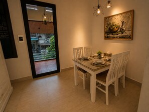 Een eethoek met een tafel voor vier personen, stoelen, een schilderij aan de muur en uitzicht op het buitenbalkon.