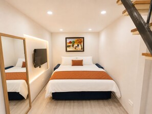 A hotel room with a bed, a TV, a painting, and a staircase. - Old Quarter 2Brs Apt . Big Balcony . FreeLaunry by Anamoi (Hà Nội)