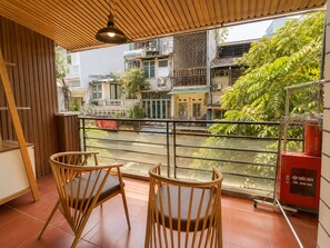 A balcony with two wooden chairs, a fire hose reel, and a view of the street and buildings. - Old Quarter 2Brs Apt . Big Balcony . FreeLaunry by Anamoi (Hà Nội)