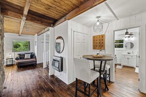 A modern interior with a wooden ceiling, a dining area with a round table, and a kitchen with white cabinets. - Pond in the Pines | Aska Farm Stay + Fishing (Blue Ridge)